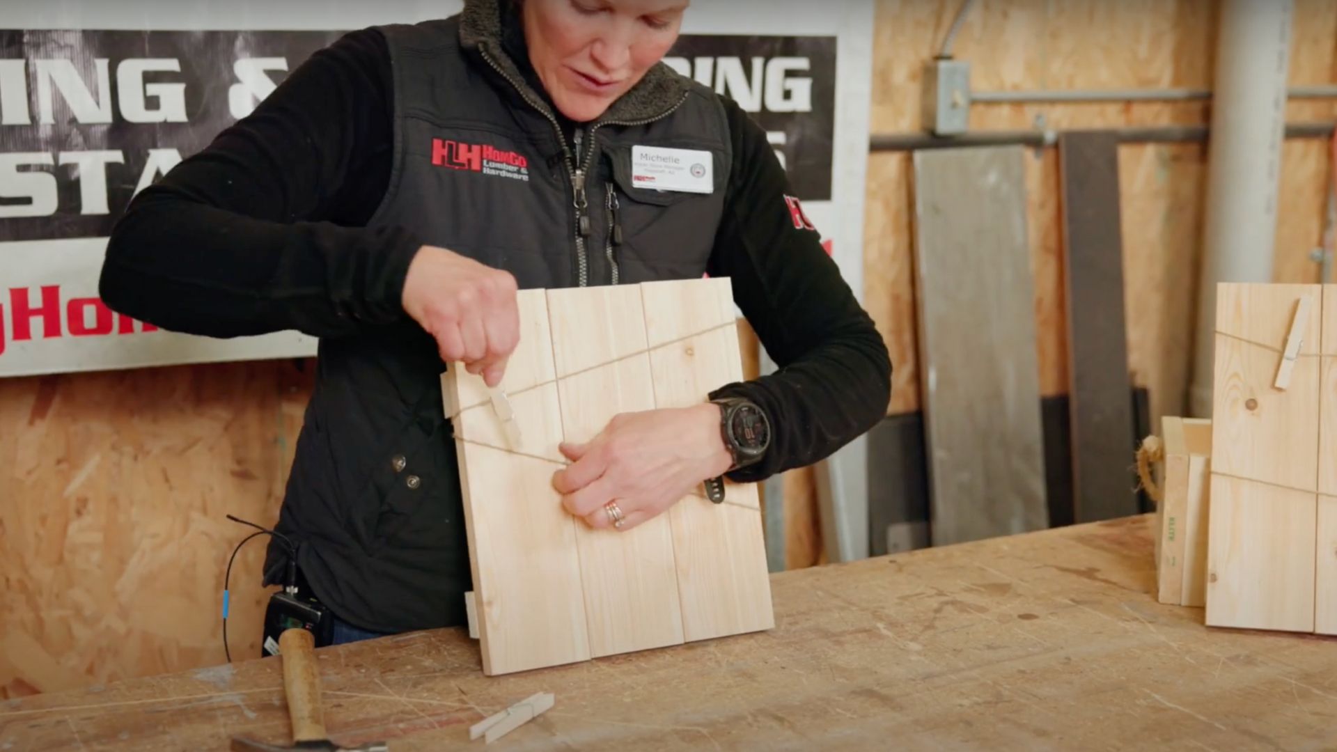 woman attaching clothespins to twine that is wrapped around wooden boards 